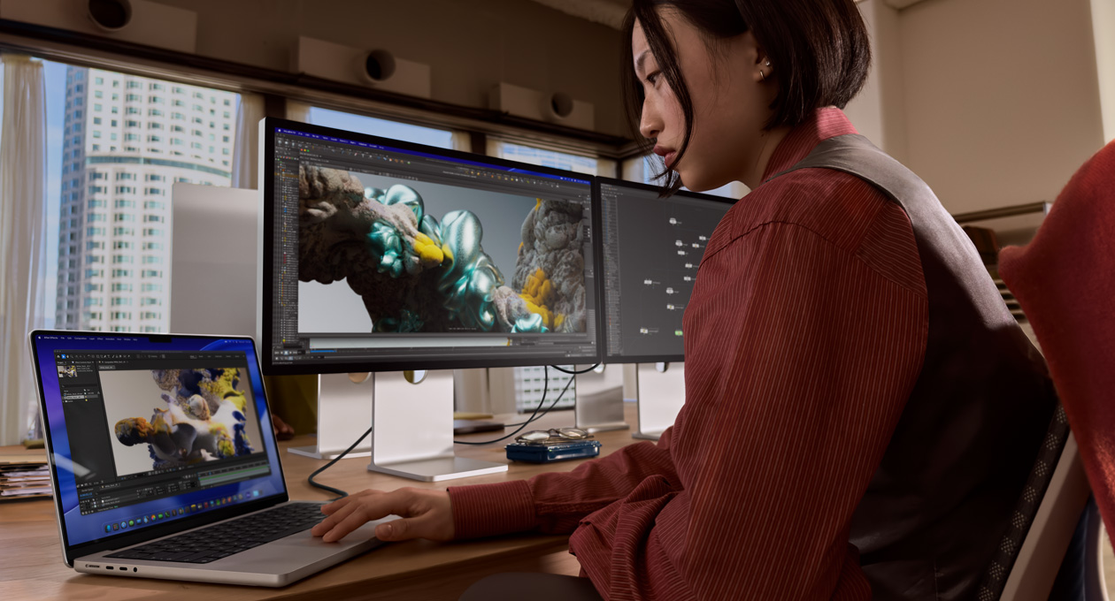 Ένα άτομο σε χώρο γραφείου εργάζεται σε laptop MacBook συνδεδεμένο με Studio Display XDR μέσω θύρας Thunderbolt 5