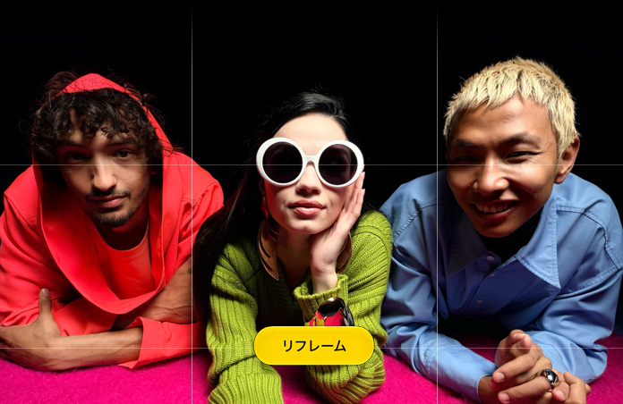 ピンク色の台の上で前に身を乗り出している3人の人物を撮影した明るい色合いのクローズアップ写真。写真上にグリッドと「リフレーム」ボタンが表示されている