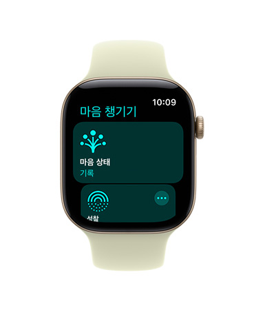 ‘마음 챙기기’ 앱이 열려 있고 오른쪽 옆면에 Digital Crown이 보이는 로즈 골드 색상 알루미늄 케이스의 Apple Watch Series 11, 그리고 라이트 블러시 스포츠 밴드