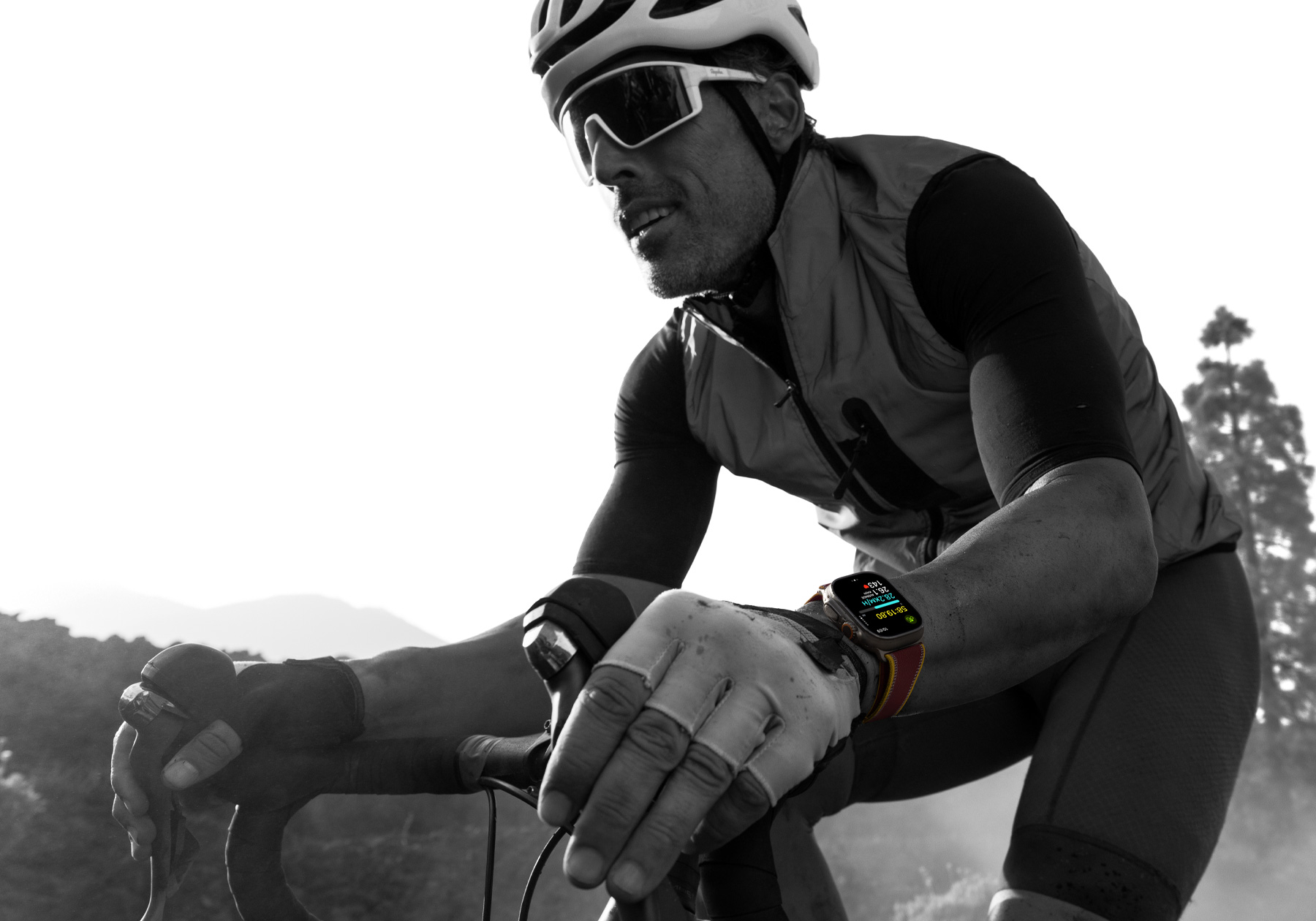 A person riding a road bike while wearing Apple Watch Ultra 4, screen shows cycling metrics