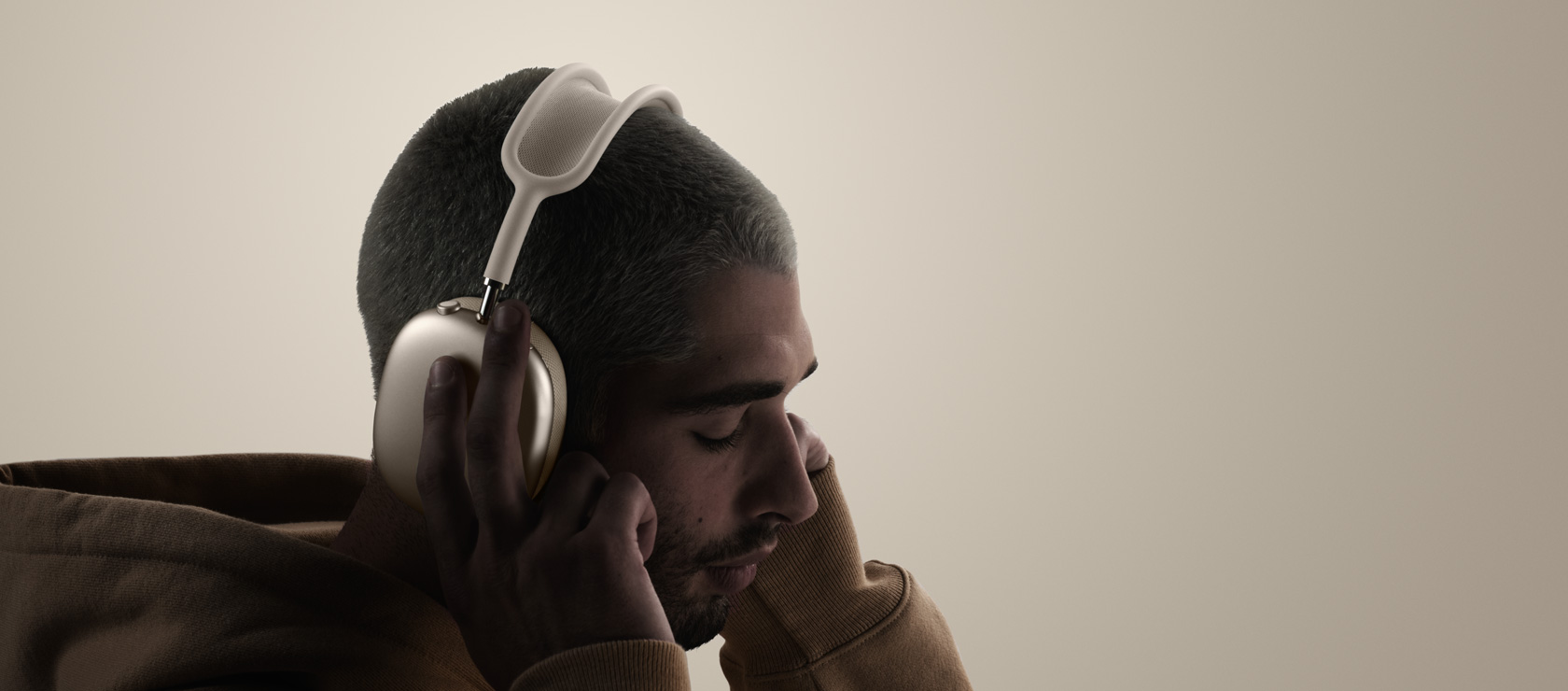 Osoba nosi slušalice AirPods Max 2, bočna strana, dodiruje jastučiće za uši