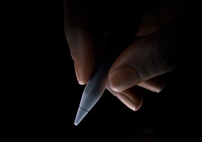 Korisnik drži donju trećinu olovke Apple Pencil Pro između palca i kažiprsta, spreman početi pisati.