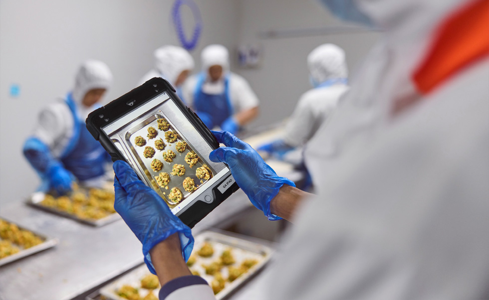 Een medewerker voert kwaliteitscontroles uit op een iPad.