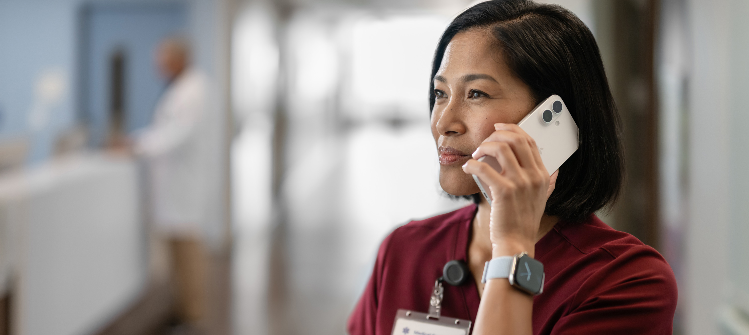 Un’infermiera in uniforme rossa che telefona con il suo iPhone.