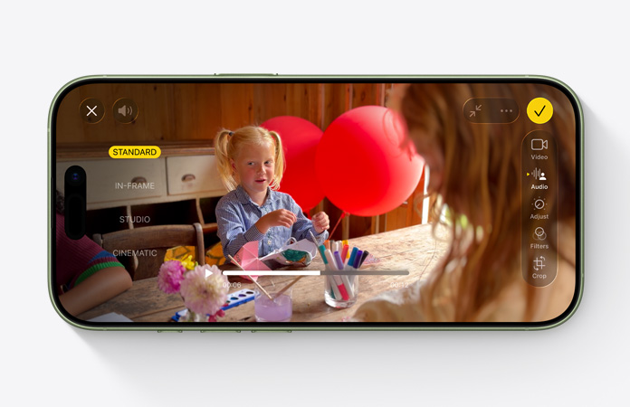 „iPhone 17“ iš priekio, vaizdo įrašas su garso derinimo funkcija, kuriame matomas su balionais prie stalo žaidžiantis vaikas