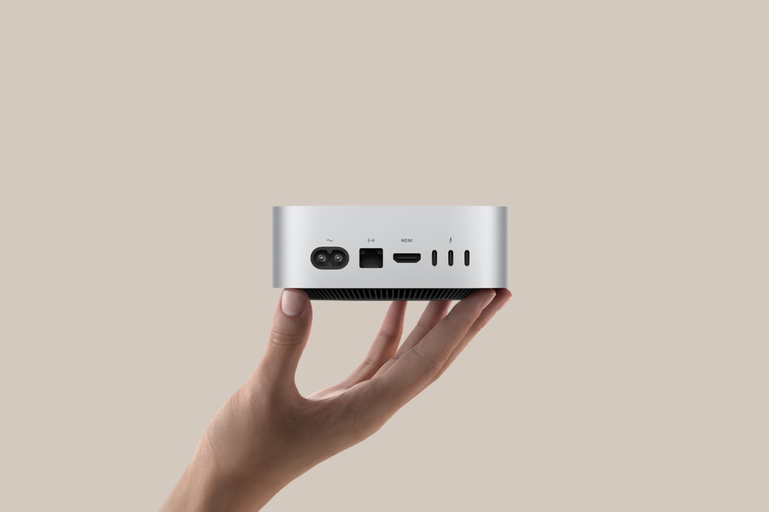 Ασημί Mac mini που δείχνει τις πίσω θύρες, πάνω στα δάχτυλα ενός ατόμου