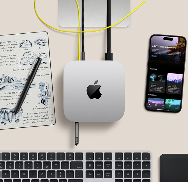 Κάτοψη ασημί Mac mini με καλώδια και μονάδα flash συνδεδεμένα σε θύρες, σε διαμόρφωση γραφείου με ασύρματο πληκτρολόγιο, trackpad, iPhone και σημειωματάριο