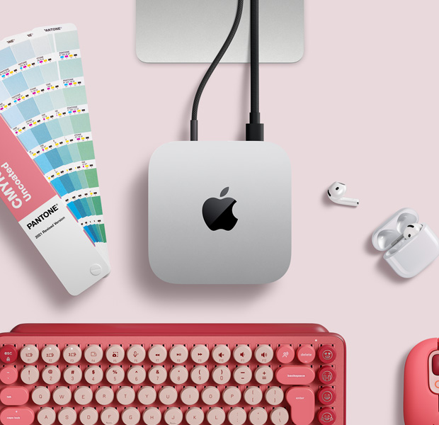 Κάτοψη ασημί Mac mini σε διαμόρφωση γραφείου με AirPods, ροζ ασύρματο πληκτρολόγιο, ροζ ασύρματο ποντίκι και δειγματολόγιο χρωμάτων